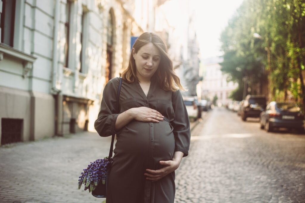 An expectant mother walks on a city street in summer, heading towards her prenatal depression treatment in Park Ridge.